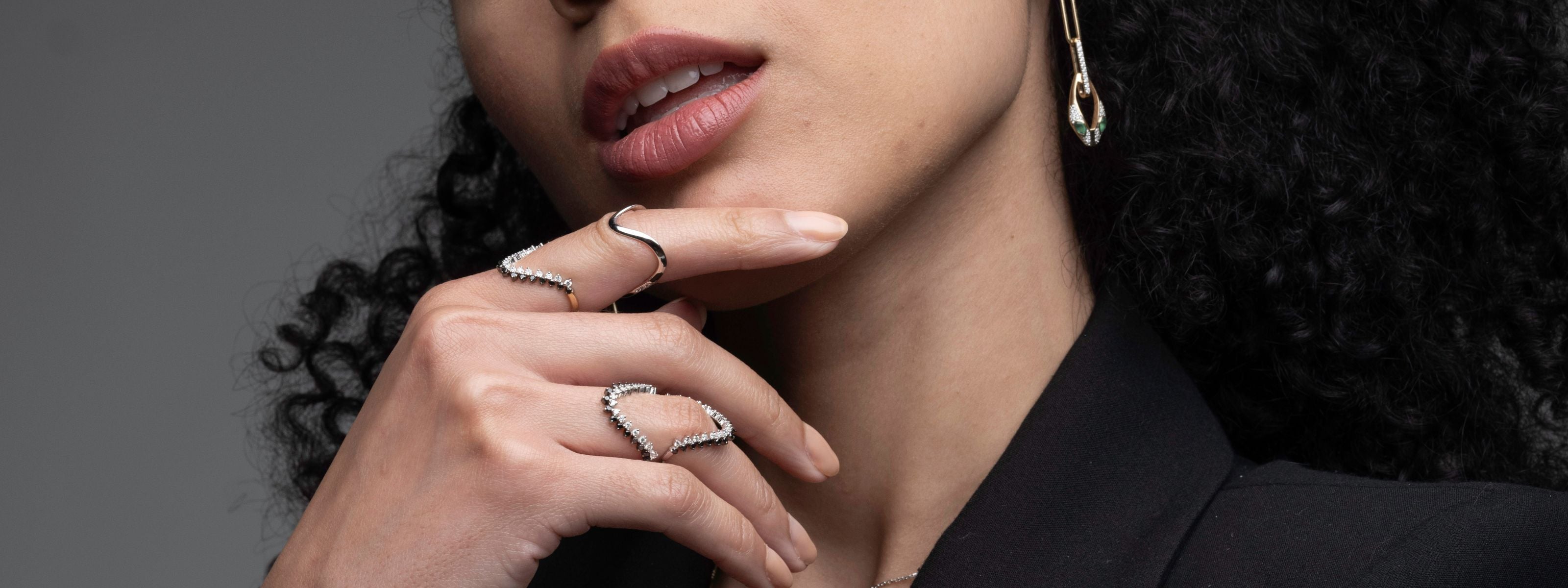 Woman wearing multiple rings on her fingers with a dark background
