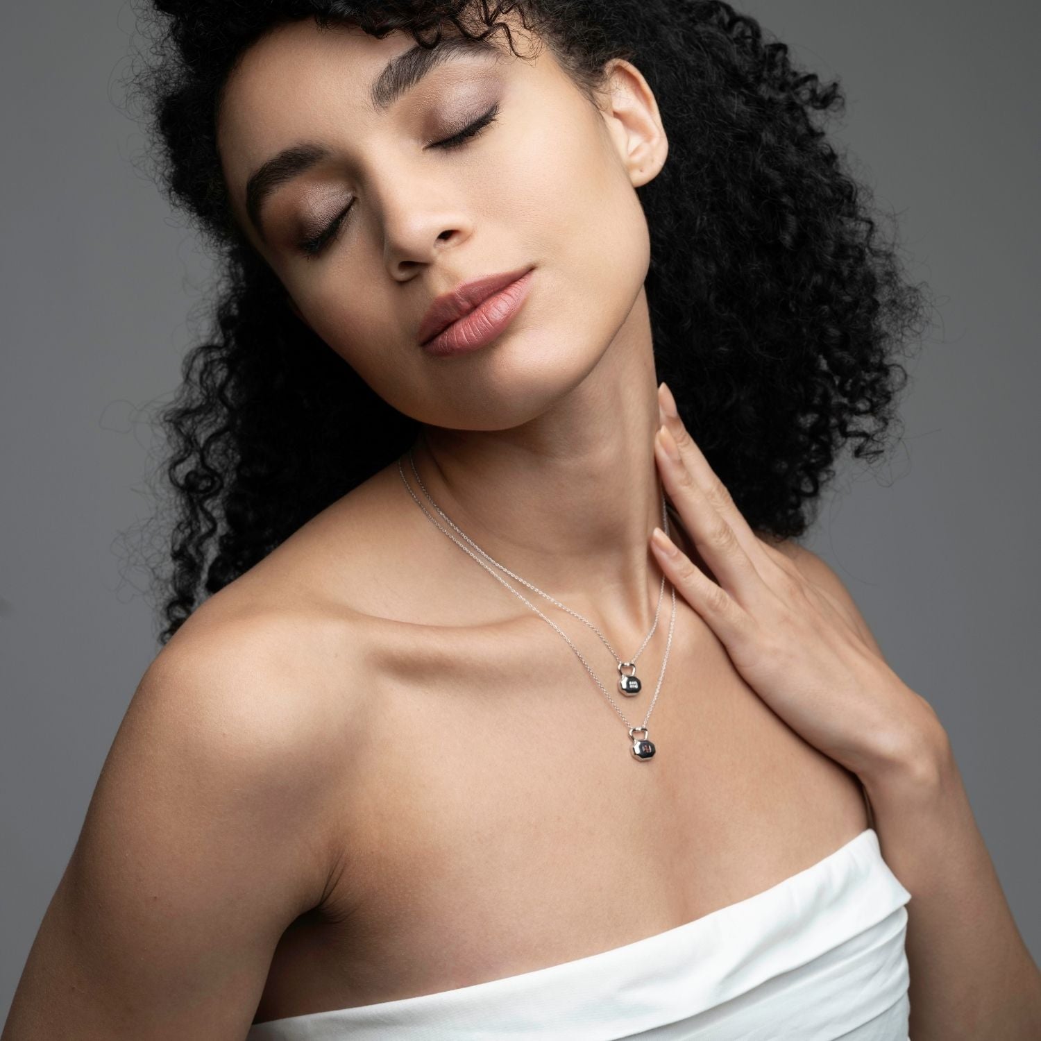Woman wearing April diamond birthstone lock necklace in silver with layered chains from Inessa Milestones Collection