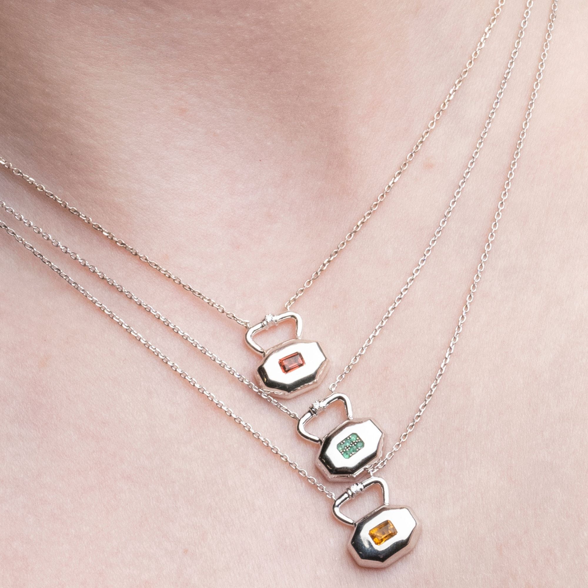 Three birthstone lock pendants shown layered displaying gemstone brilliance and styling versatility on silver chains