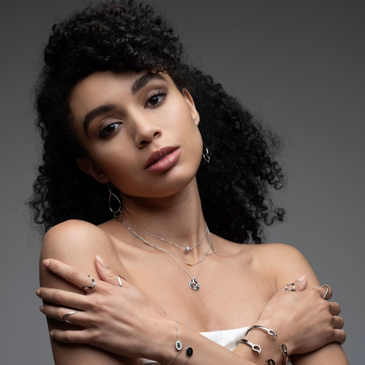 Inessa black ceramic lotus necklace styled with silver rings and bracelets, complete jewelry look