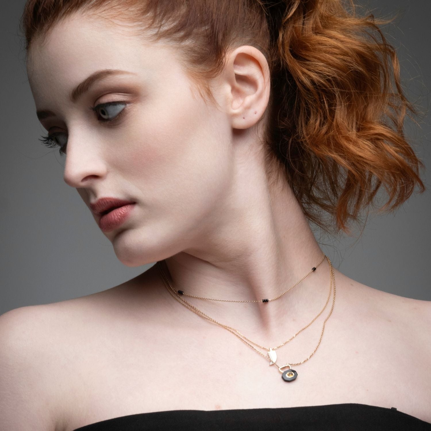 Close-up of black onyx trio layering necklace showing three bead clusters on gold chain