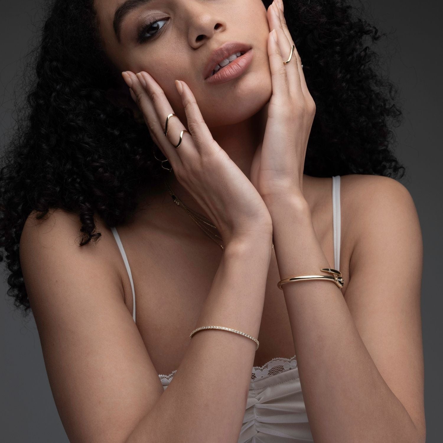 Woman wearing 14k gold diamond tennis bracelet stacked with other bracelets from Inessa Stackable Collection