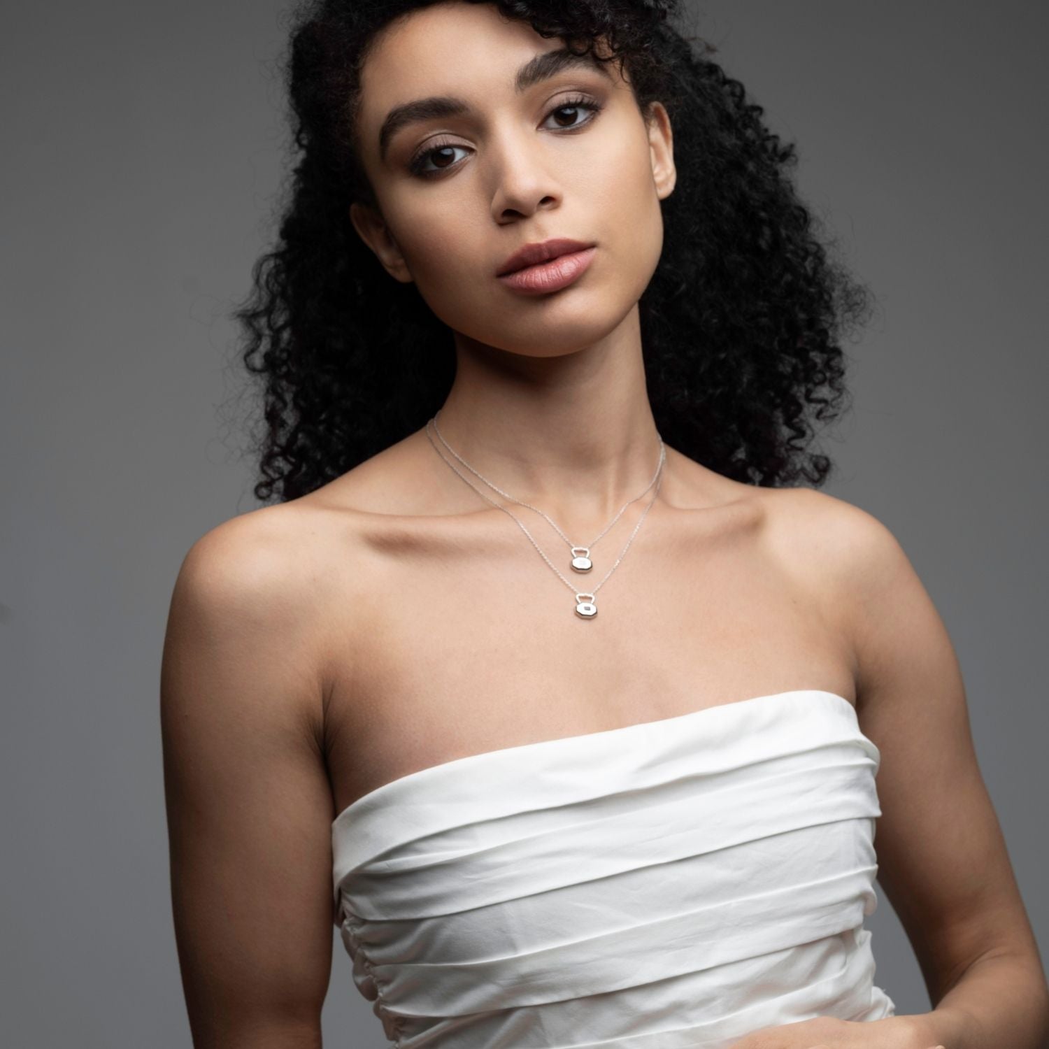 Woman wearing January garnet birthstone lock necklace with layered silver chains from Milestones Collection