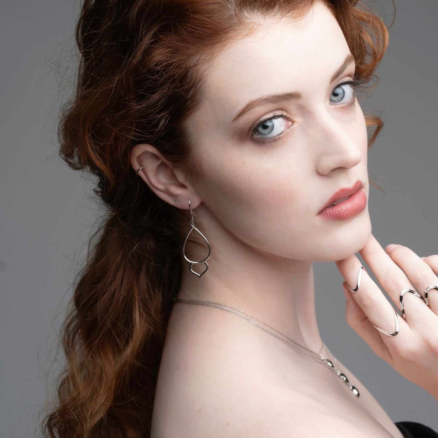 Woman wearing silver lotus bud hoop earrings with black diamonds from Inessa Jewelry Strength Collection