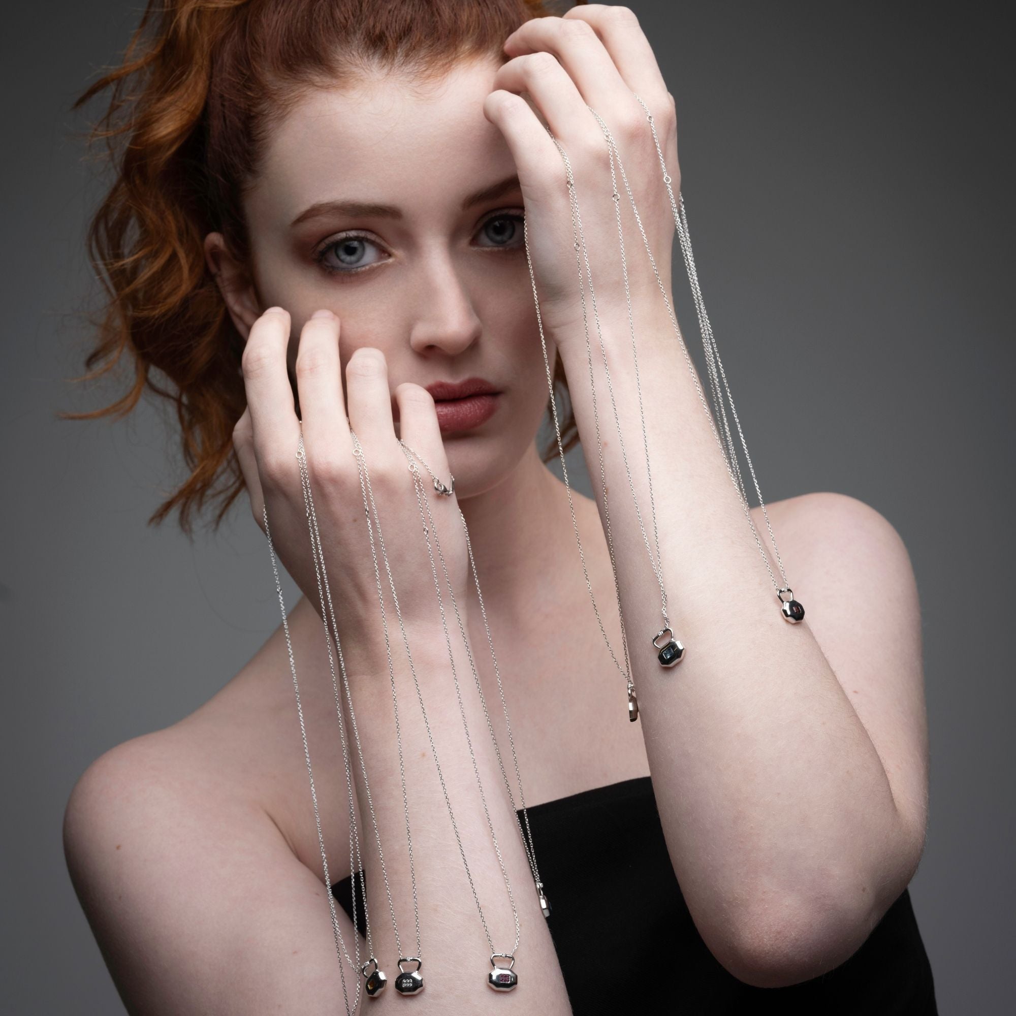 Multiple birthstone lock pendants from Inessa Milestones Collection displayed artistically through model's hands