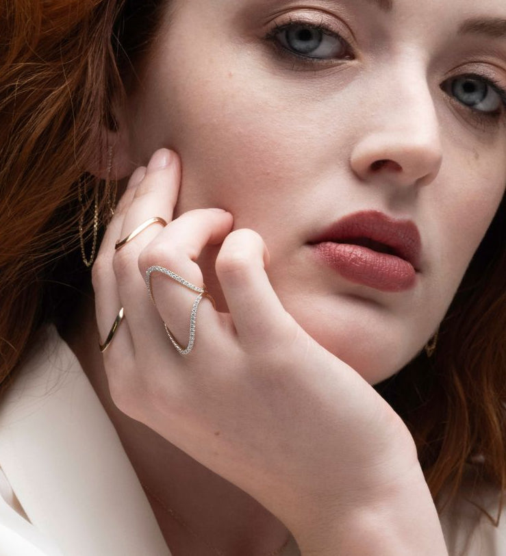 Woman wearing pave sculptural wave rings with a neutral background