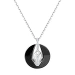 Close-up of serpent pendant on black ceramic coin with sterling silver chain, meaningful transformation necklace