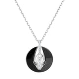 Close-up of serpent pendant on black ceramic coin with sterling silver chain, meaningful transformation necklace