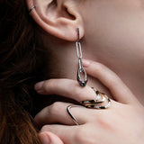 Close-up of silver serpent chain drop earring showing ruby eyes and black diamond scales construction