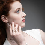 Woman wearing silver serpent chain drop earrings with ruby eyes styled with rings and necklaces