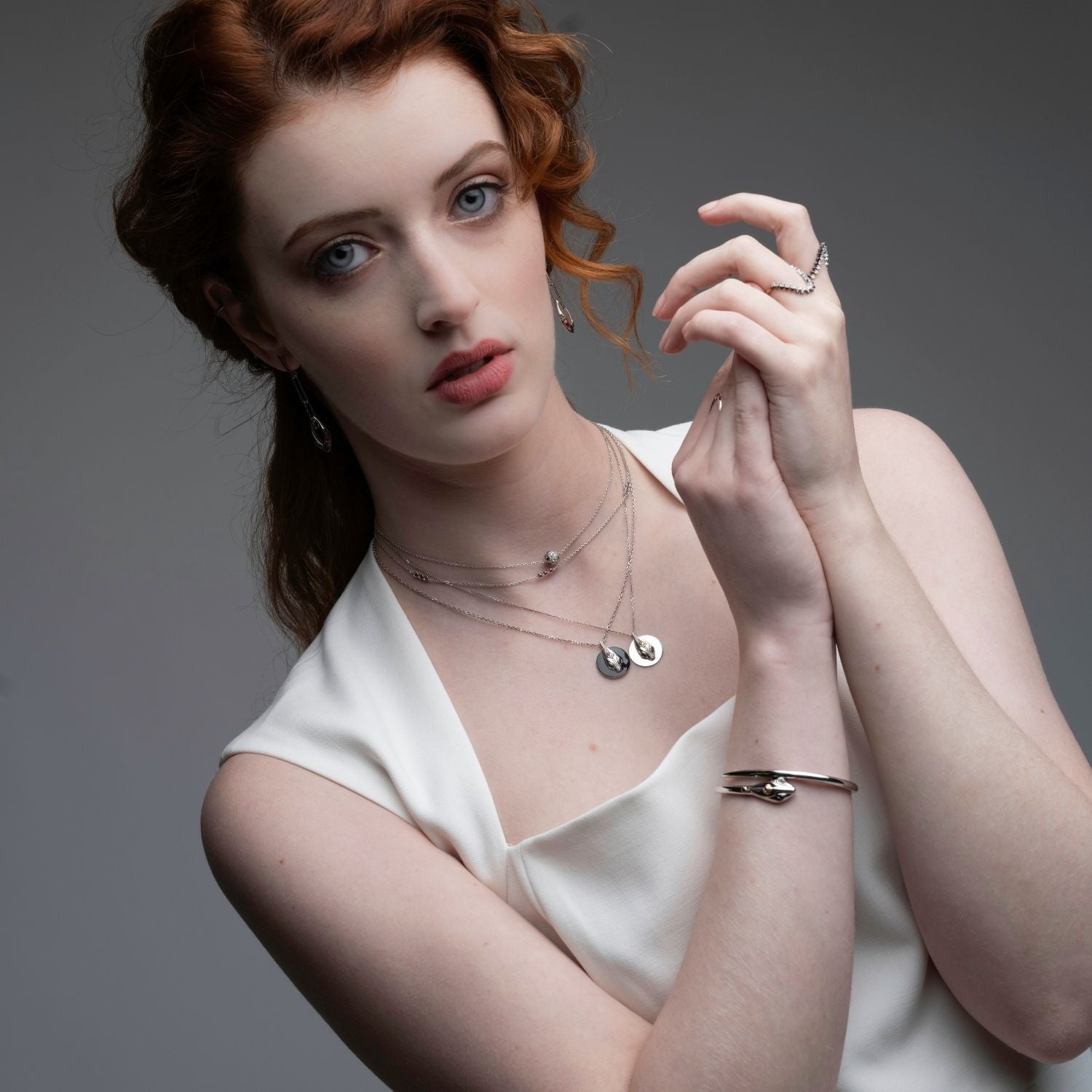 Woman wearing serpent black ceramic coin pendant with layered necklaces and rings from Renewal Collection