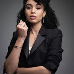 Professional woman wearing 14k gold serpent hinged bangle with layered necklaces and rings