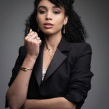 Professional woman wearing 14k gold serpent hinged bangle with layered necklaces and rings