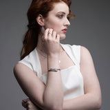 Woman wearing sterling silver serpent hinged bangle with rings and necklaces from Renewal Collection