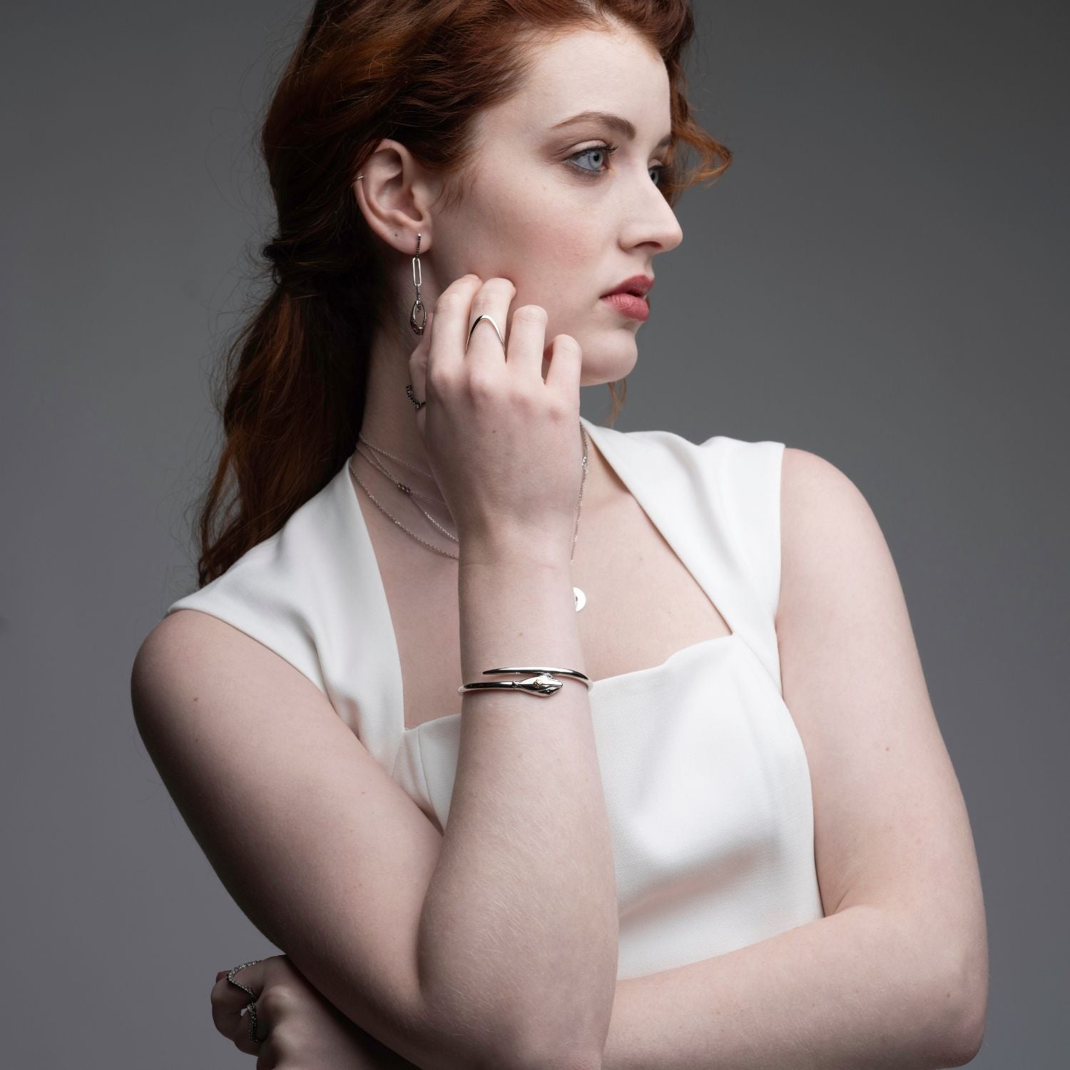 Woman wearing sterling silver serpent hinged bangle with rings and necklaces from Renewal Collection