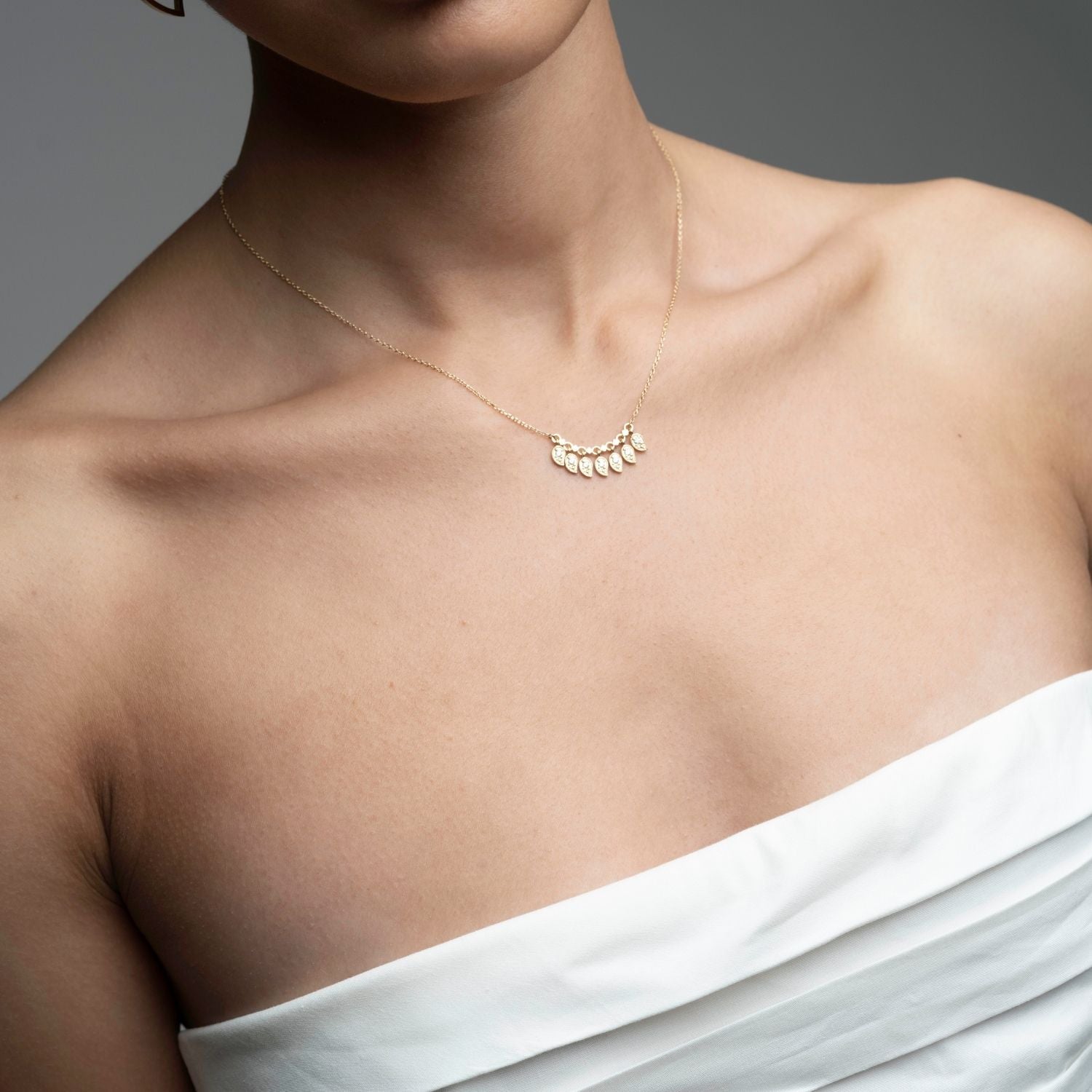 Seven mango diamond necklace in 14k gold worn solo showing movement and sparkle on model