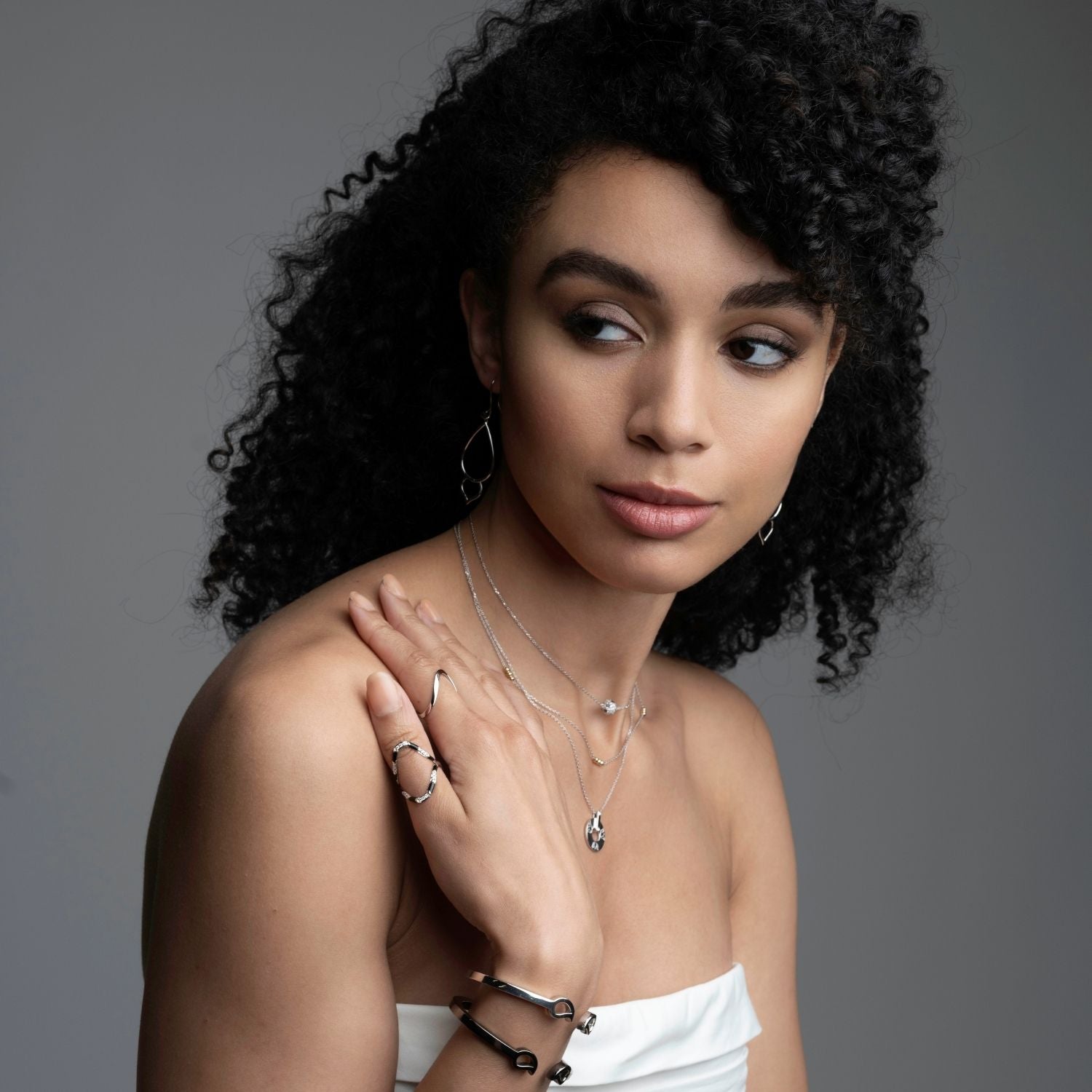 Woman wearing silver wave ring with black ceramic and diamonds styled with layered necklaces