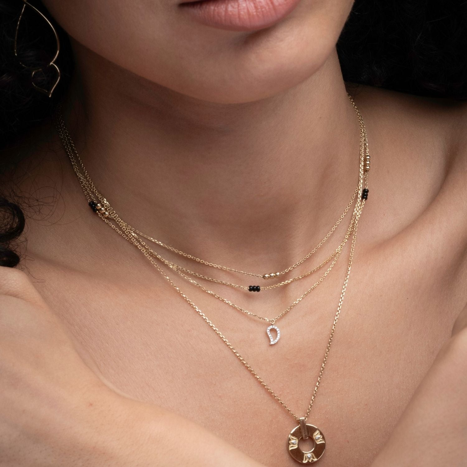 Close-up of 14k gold mango diamond outline necklace layered with multiple chains from Love Collection