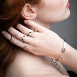 Close-up detail of wave rings with black ceramic segments and diamonds in 14k gold