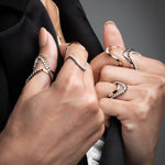 Close-up of wave statement rings with black and white diamonds showing stacking capability